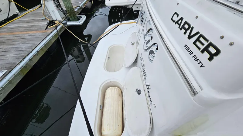 Slide: The Image of 2000 Carver 450 Voyager Pilothouse docked, showcasing rear deck and branding. - 19