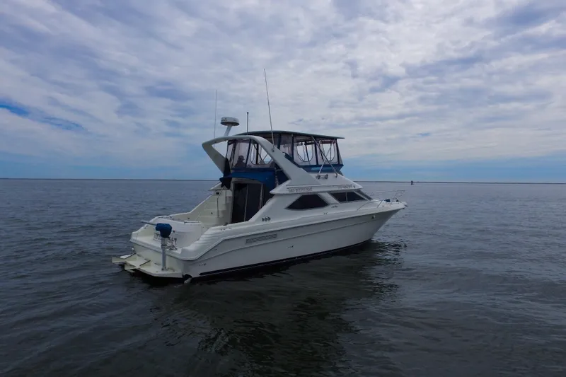 Slide: The Image of 1993 Sea Ray 440 Express Bridge yacht on calm waters under a cloudy sky. - 5