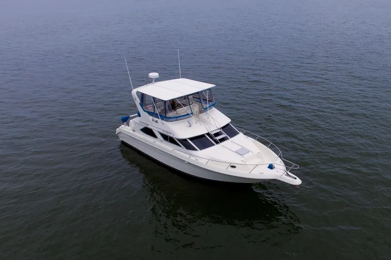 Slide: The Image of 1993 Sea Ray 440 Express Bridge yacht on calm water, showcasing sleek design and spacious deck. - 9