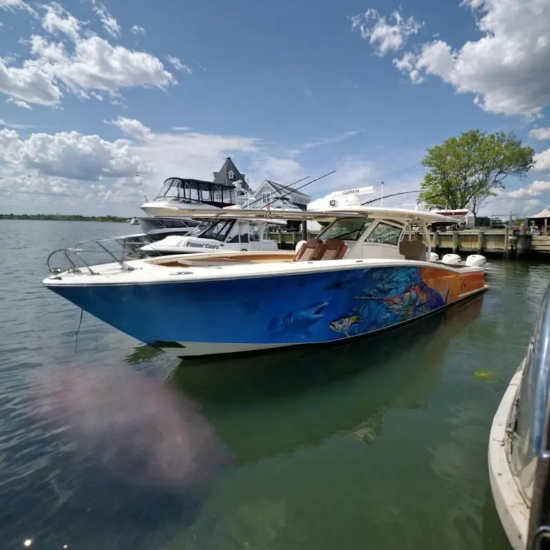 The Image of A 2019 Scout 380 LXF boat on the water, surrounded by other boats and a dock. - 0