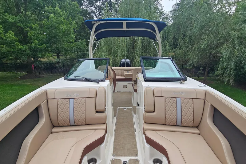 Slide: The Image of 2017 Sea Ray SDX 240 Outboard boat interior with tan seating and blue canopy. - 35