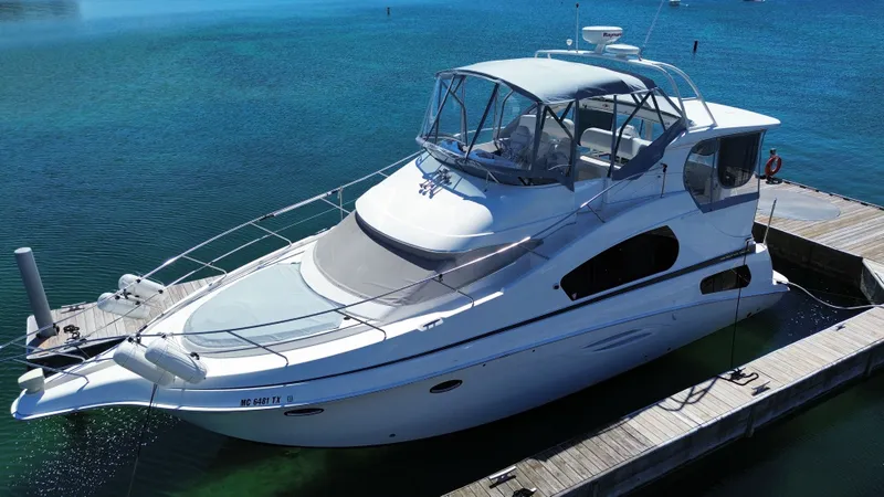 Slide: The Image of 2003 Silverton 39 Motor Yacht docked, featuring an enclosed flybridge and clear blue water setting. - 2