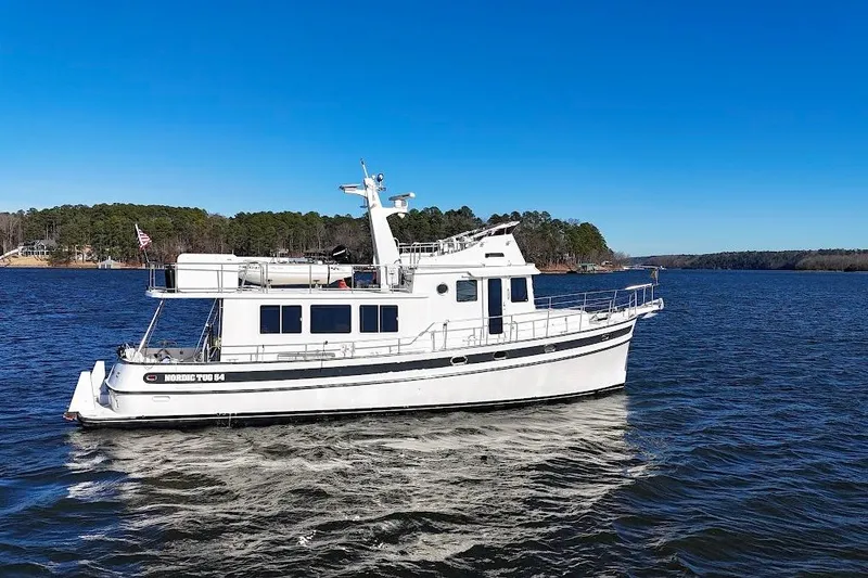 Slide: The Image of 2007 Nordic Tug 54 cruising on a serene lake under a clear blue sky. - 10