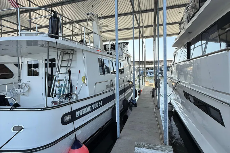 Slide: The Image of 2007 Nordic Tug 54 docked in a marina, side view under covered shelter. - 15