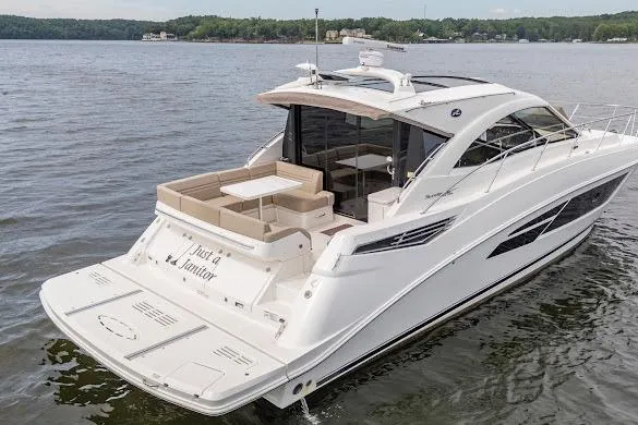Slide: The Image of 2016 Sea Ray Sundancer 510 yacht cruising on a serene lake with lush green shoreline. - 7