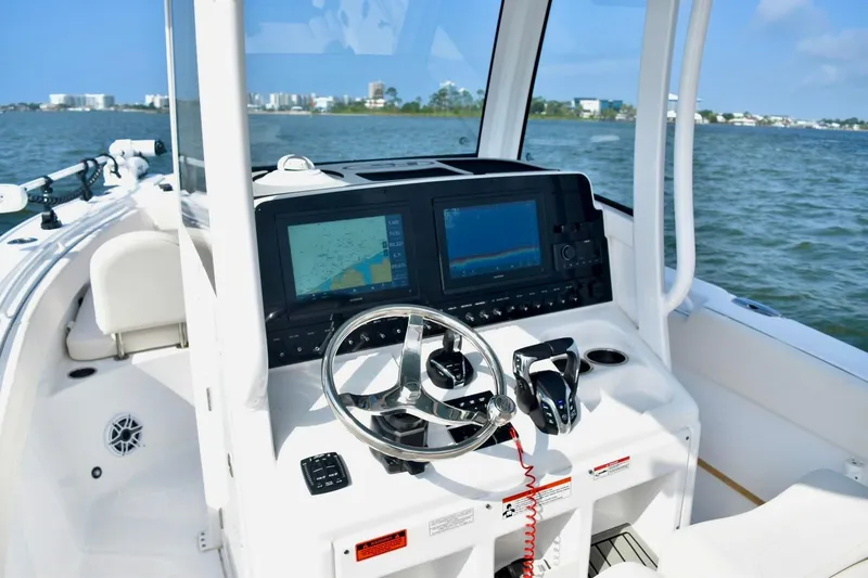 Slide: The Image of 2026 Sea Hunt Ultra 265 SE boat dashboard with navigation screens and steering wheel on open water. - 9