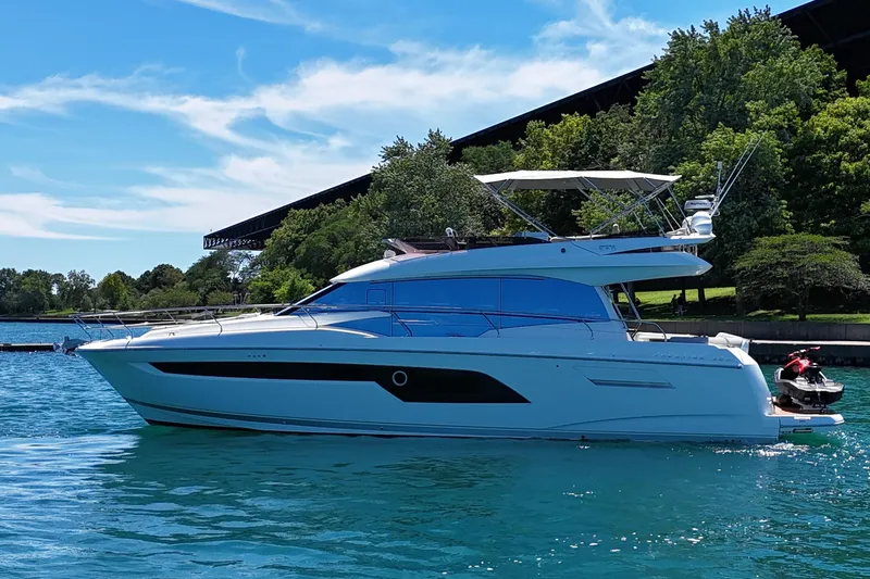 The Image of 2022 Prestige 520 yacht on a serene lake with lush greenery. - 0