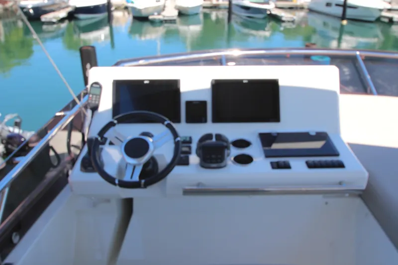 Slide: The Image of Control panel of a 2022 Prestige 520 yacht with steering wheel and navigation screens. - 100