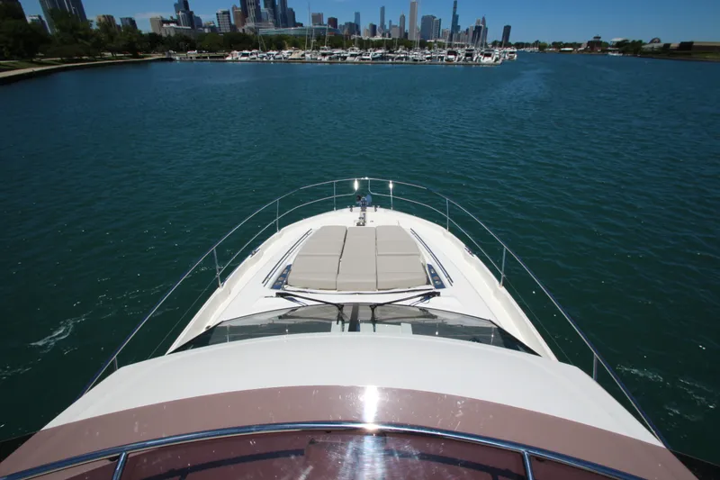 Slide: The Image of 2022 Prestige 520 yacht cruising on a serene lake with city skyline in background. - 102