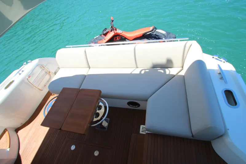 Slide: The Image of Luxury seating area on 2022 Prestige 520 yacht with jet ski on turquoise water. - 116
