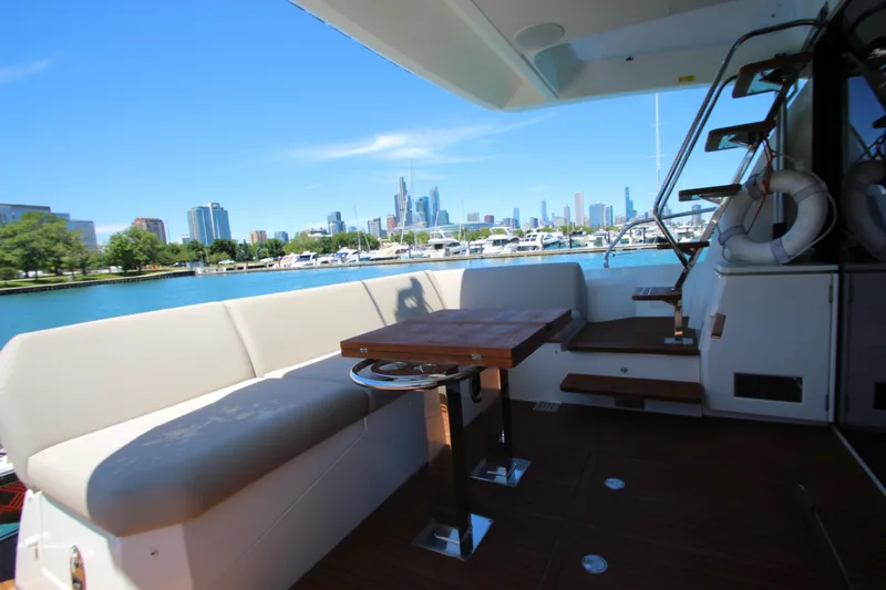 Slide: The Image of Luxurious 2022 Prestige 520 yacht deck with city skyline view, featuring seating and table. - 129