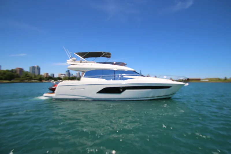 Slide: The Image of 2022 Prestige 520 yacht cruising on a sunny day with city skyline backdrop. - 131