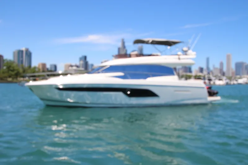 Slide: The Image of Blurry image of a 2022 Prestige 520 yacht on water with city skyline background. - 133
