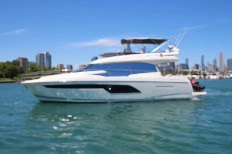 Slide: The Image of Luxury 2022 Prestige 520 yacht cruising on a sunny day with city skyline backdrop. - 134