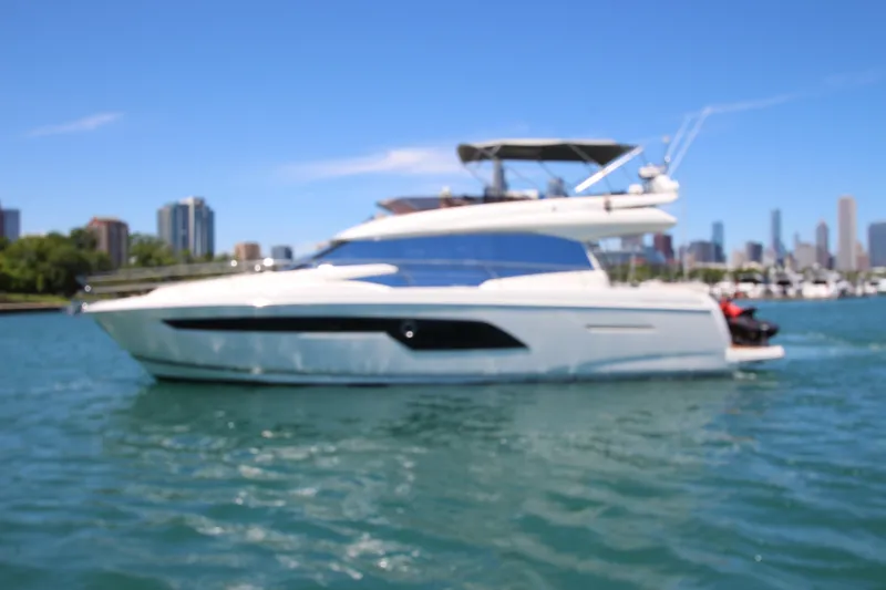 Slide: The Image of Luxury 2022 Prestige 520 yacht cruising on a sunny day with city skyline backdrop. - 135