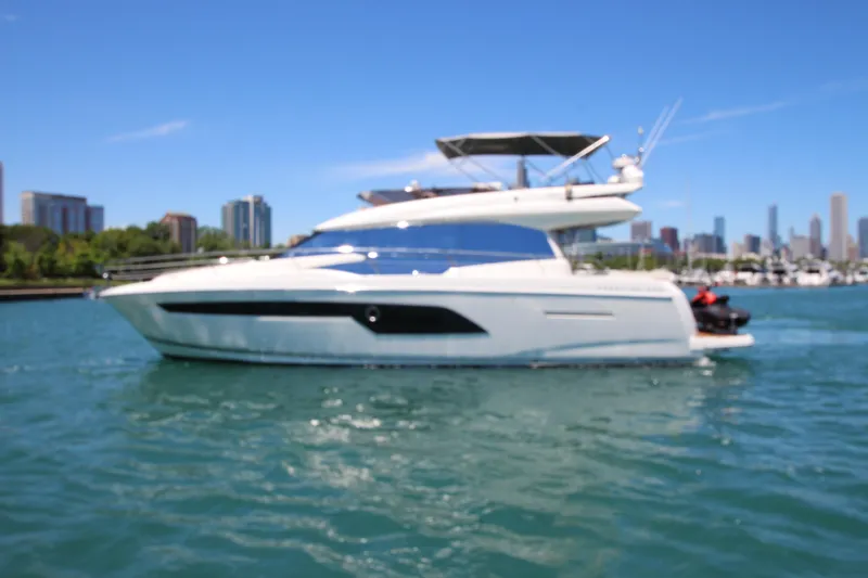 Slide: The Image of Luxurious 2022 Prestige 520 yacht cruising on a sunny day with city skyline backdrop. - 136
