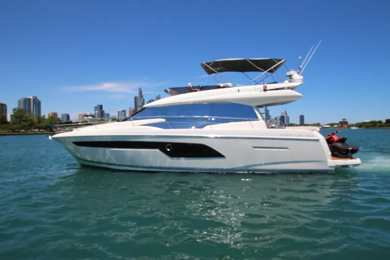 Slide: The Image of 2022 Prestige 520 yacht cruising on a sunny day with city skyline in the background. - 137