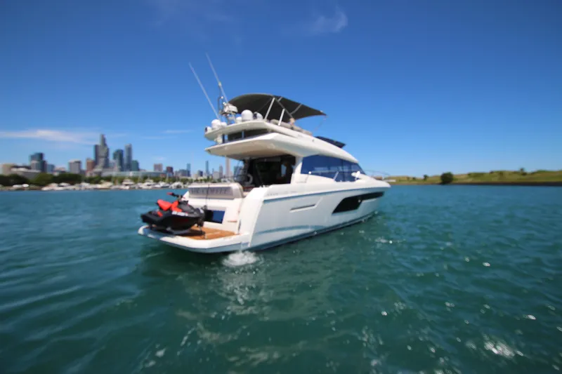 Slide: The Image of 2022 Prestige 520 yacht cruising on a sunny day with city skyline in background. - 142
