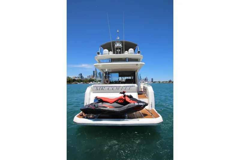 Slide: The Image of Luxury 2022 Prestige 520 yacht with jet ski on deck, city skyline in background. - 143