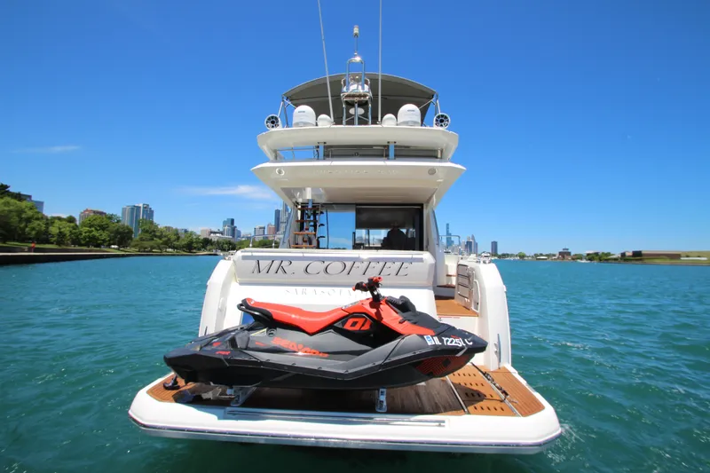 Slide: The Image of 2022 Prestige 520 yacht with jet ski on deck, city skyline in background. - 145
