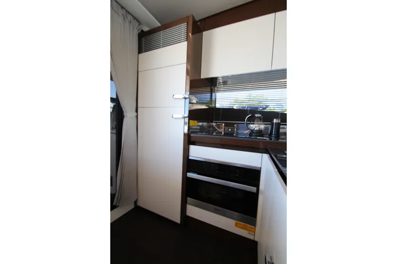 Slide: The Image of Modern kitchen interior on a 2022 Prestige 520 yacht, featuring sleek cabinetry and appliances. - 24