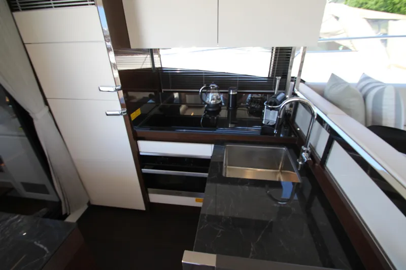 Slide: The Image of Modern kitchen interior on 2022 Prestige 520 yacht, featuring sleek countertops and stainless steel sink. - 26