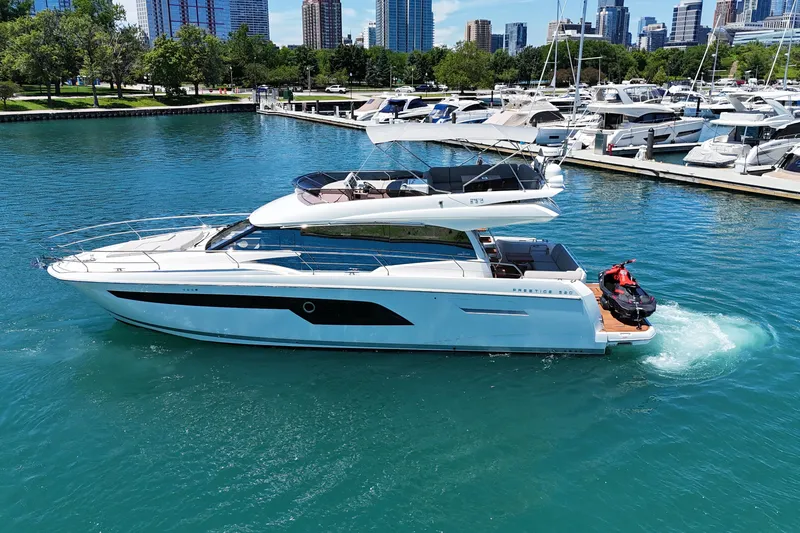 Slide: The Image of Luxury 2022 Prestige 520 yacht cruising in a marina with city skyline backdrop. - 7
