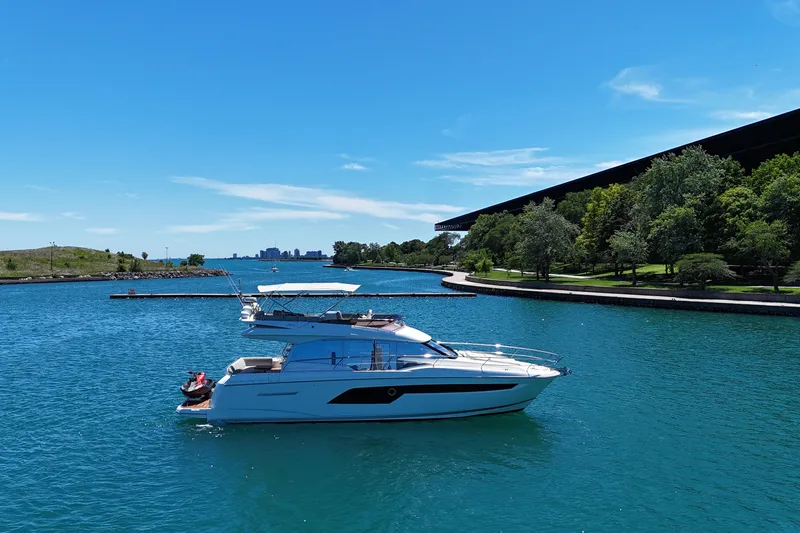 Slide: The Image of 2022 Prestige 520 yacht cruising on a serene blue lake under a clear sky. - 9