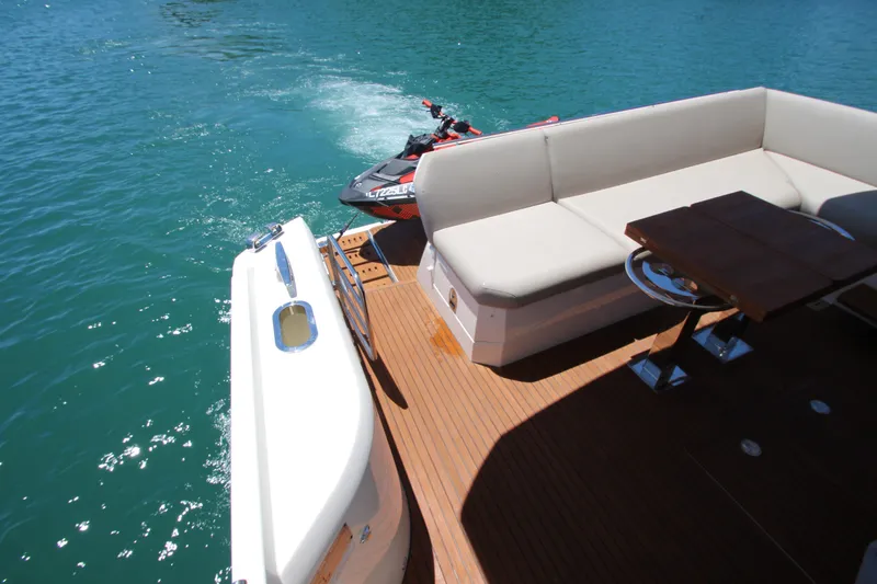 Slide: The Image of Luxurious 2022 Prestige 520 yacht deck with seating and jet ski on turquoise water. - 90