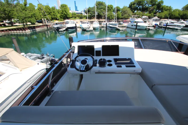 Slide: The Image of Cockpit of 2022 Prestige 520 yacht docked in a marina with lush greenery. - 99