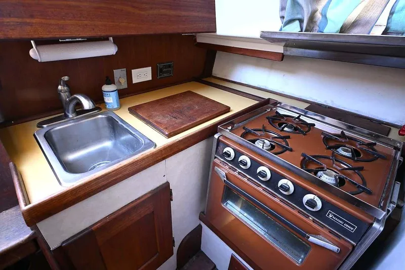 Slide: The Image of 1977 Mercator Offshore boat kitchen with stove, sink, and wooden cabinetry. - 14