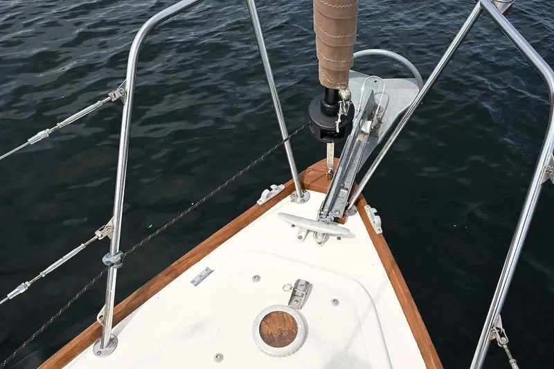 Slide: The Image of Bow of 1977 Mercator Offshore sailboat with anchor and railing over water. - 10