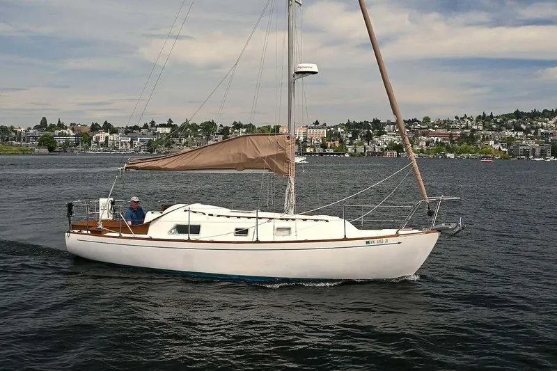 The Image of 1977 Mercator Offshore sailboat cruising on a scenic lake with cityscape background. - 1