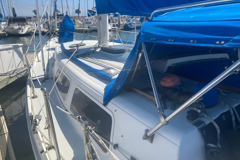 Slide: The Image of 1979 CAL 34-III sailboat docked, featuring blue canopy and white deck in marina. - 4