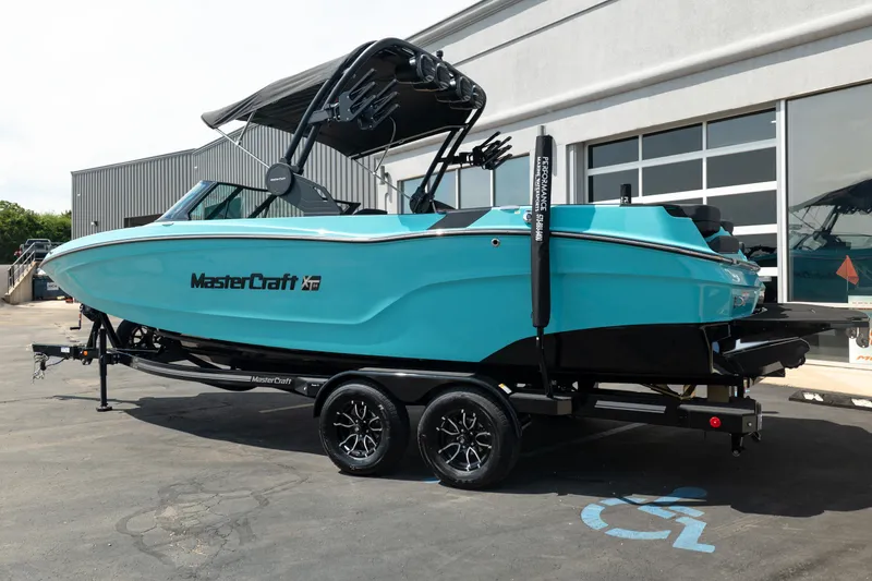 Slide: The Image of 2026 MasterCraft XT24 boat in vibrant turquoise on a trailer outside a building. - 4