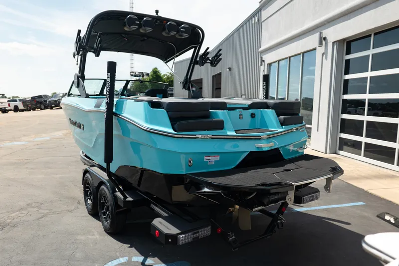 Slide: The Image of 2026 MasterCraft XT24 boat in vibrant blue on a trailer, parked outside a modern building. - 5