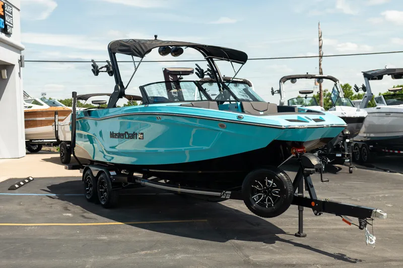Slide: The Image of 2026 MasterCraft XT24 boat in vibrant blue on a trailer at a dealership. - 13
