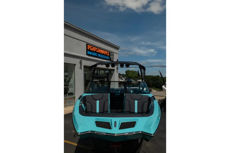 Slide: The Image of 2026 MasterCraft XT24 boat in turquoise, parked outside a marine dealership. - 16