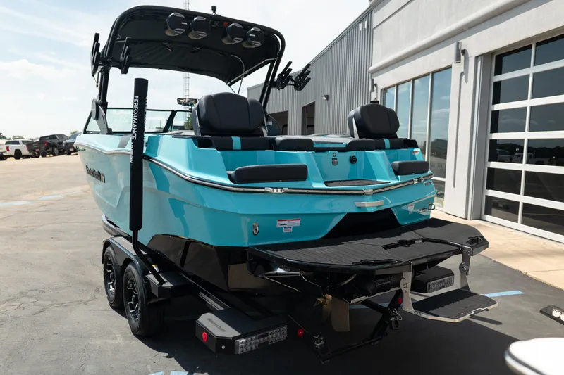 Slide: The Image of 2026 MasterCraft XT24 boat in vibrant blue, parked on a trailer outside a modern building. - 6