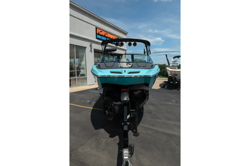Slide: The Image of 2026 MasterCraft XT24 boat in turquoise, parked outside a marine dealership. - 15