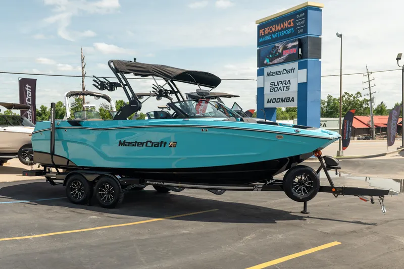 Slide: The Image of 2026 MasterCraft XT24 boat on trailer at dealership, showcasing sleek design and vibrant color. - 11