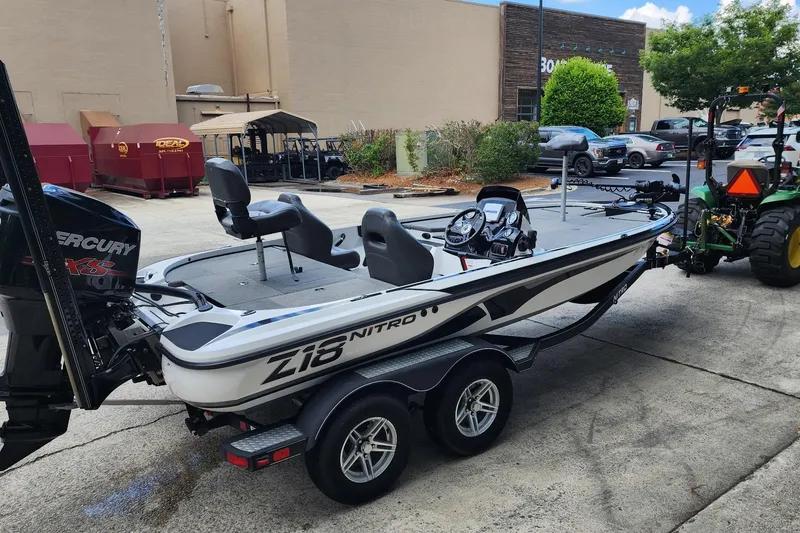 Slide: The Image of 2017 Nitro Z18 boat on trailer, parked outdoors near industrial buildings. - 2