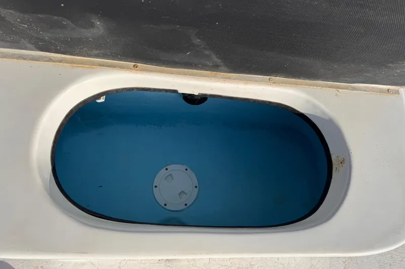 Slide: The Image of Open storage compartment on a 2006 South Shore 26 boat, featuring a blue interior. - 16