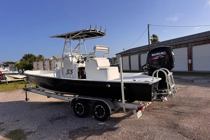 Slide: The Image of 2006 South Shore 26 boat on trailer with Suzuki outboard motor, parked outdoors. - 2