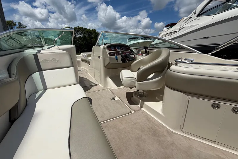 Slide: The Image of 2004 Sea Ray 240 Sundeck interior with beige seating and steering wheel under a blue sky. - 10