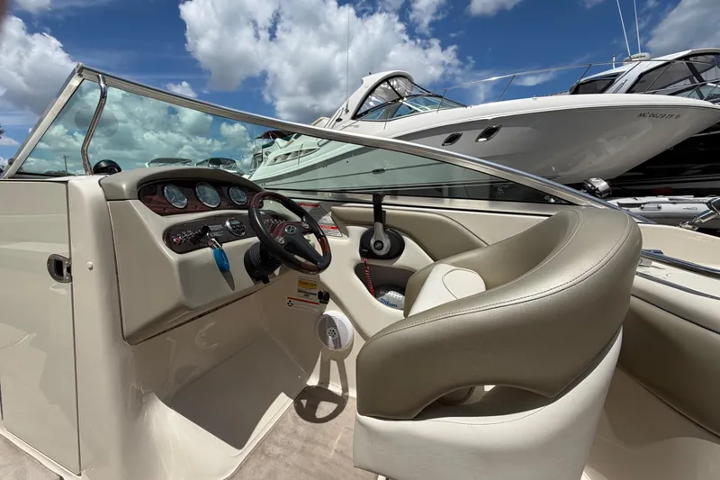 Slide: The Image of 2004 Sea Ray 240 Sundeck boat interior with steering wheel and dashboard under blue sky. - 11