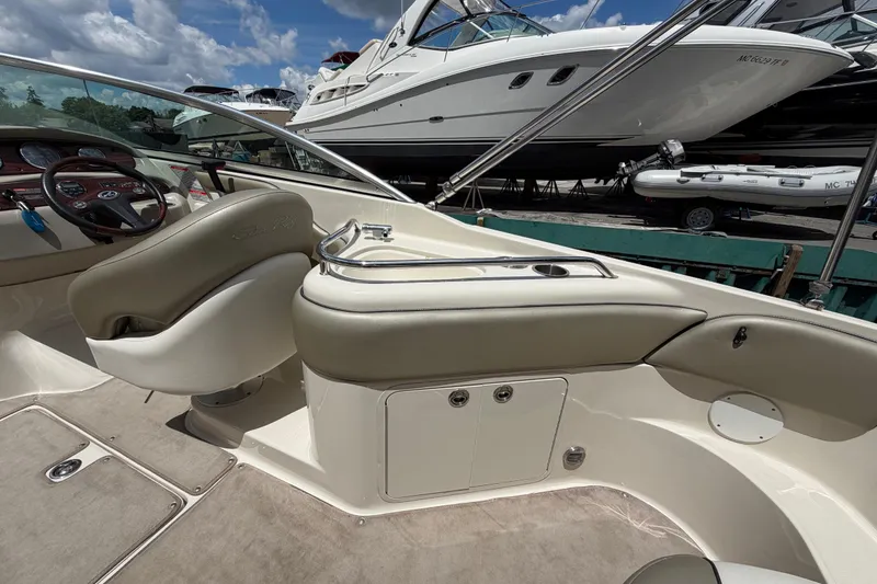 Slide: The Image of 2004 Sea Ray 240 Sundeck interior with helm, seating, and dashboard under a sunny sky. - 16