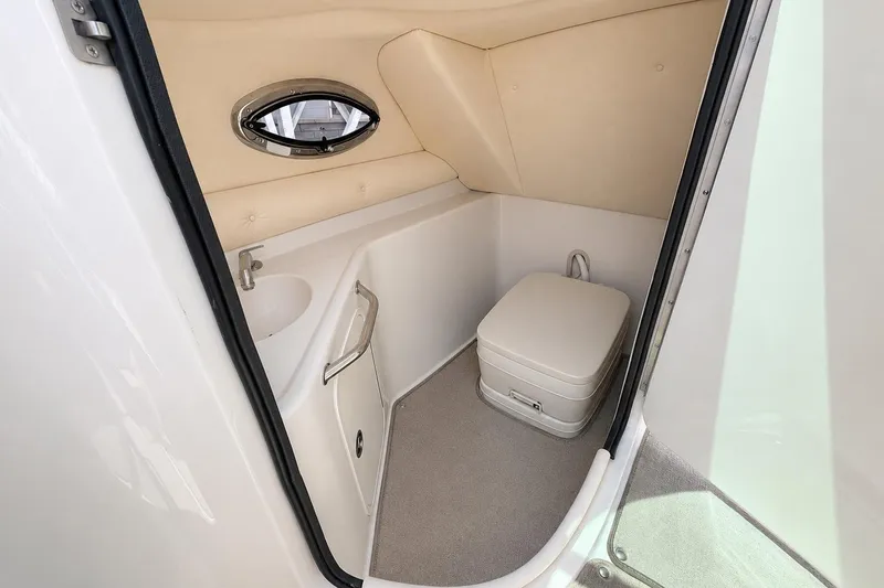 Slide: The Image of 2004 Sea Ray 240 Sundeck boat bathroom with compact toilet and sink. - 20