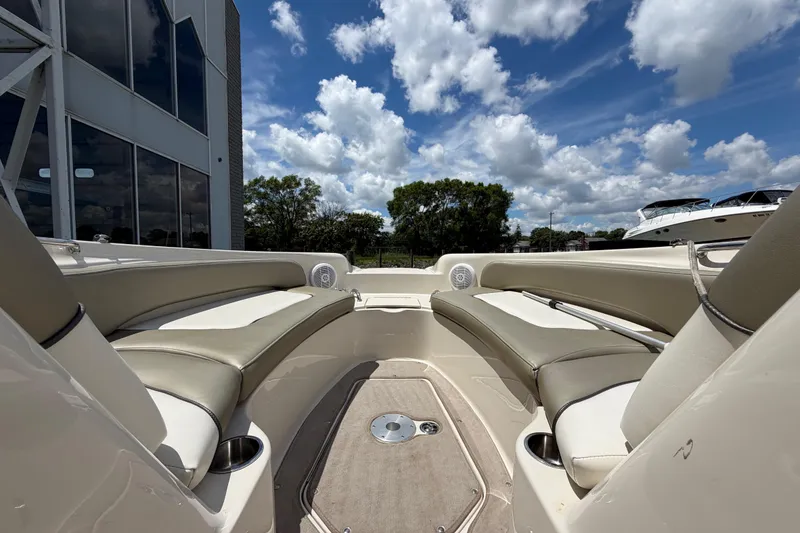 Slide: The Image of 2004 Sea Ray 240 Sundeck interior with beige seating, under a bright blue sky. - 23