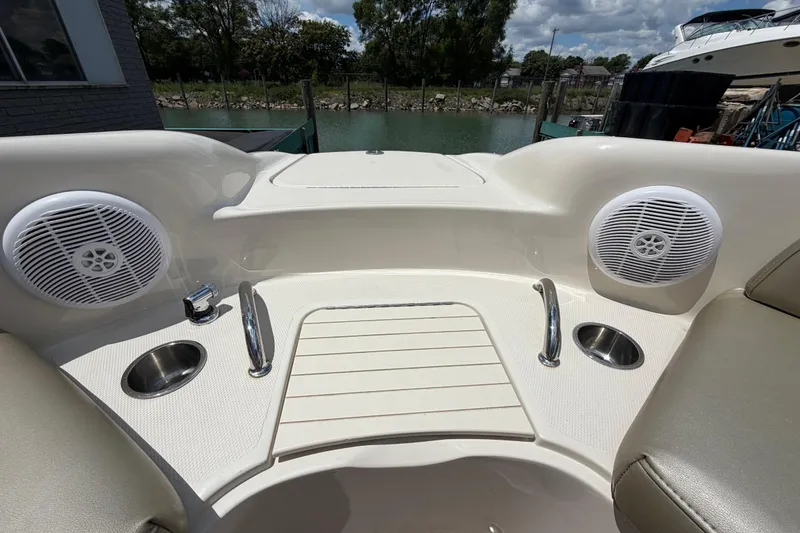 Slide: The Image of 2004 Sea Ray 240 Sundeck boat interior with speakers and cup holders, docked by the water. - 25